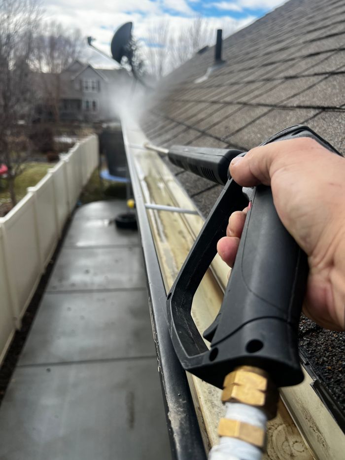 why-choose-us-01 Close-up of gutter cleaning with pressure washer, outdoors, during the day.